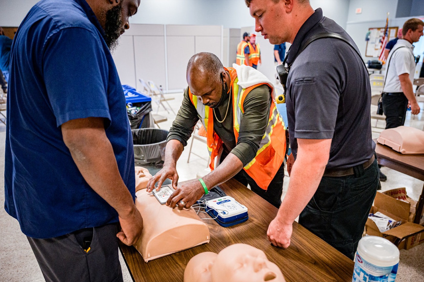 A trainer guiding a student as they place defibrillator pads on a CPR manikin.